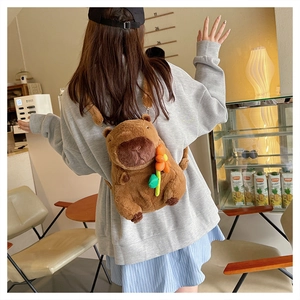 Brown capybara plush backpack with orange flower shown on a person for scale