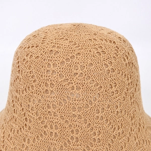 Macro shot of the hollow-out crochet pattern on a light khaki sun hat showing breathable texture
