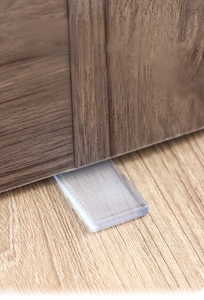 Detail of transparent wedge-shaped leveling shims stabilizing a wooden cabinet base