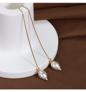 Macro detail of a 14k gold plated sterling silver box chain with a baroque pearl drop