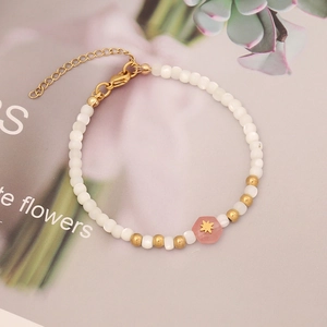 Detail of beaded bracelet with pink stone star charm and golden lobster clasp closure