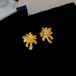 Elegant gold plated palm tree stud earrings with fine textures on black background