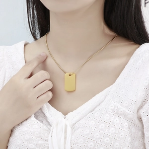 Close-up of golden rectangular pendant necklace on beaded chain worn by a model
