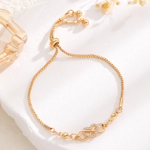 Adjustable gold heart and infinity bracelet with sparkling crystals on stone background