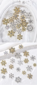Detailed view of gold and silver snowflake nail charms with sparkling rhinestones