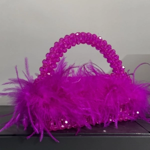 Close-up of pink handmade beaded handbag featuring fluffy ostrich feather decorations