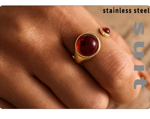 Detail of gold stainless steel open ring with red garnet stones on a hand