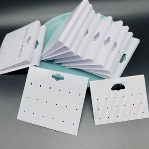 Close-up of white PVC earring display cards with multiple holes and hanging hooks