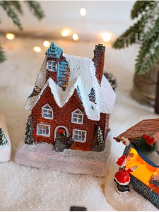 Close-up of a glowing resin Christmas candy store house with a snowy roof and warm lights