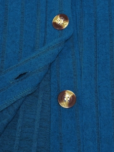 Dettaglio maglia a coste blu pavone con due bottoni ambrati testurizzati sulla felpa