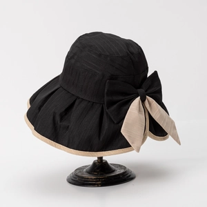 Detail of elegant black bucket hat with large beige bow accent and textured fabric