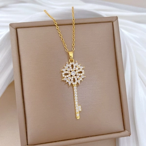 Elegant gold hollow flower key necklace with sparkling crystals in a beige jewelry box
