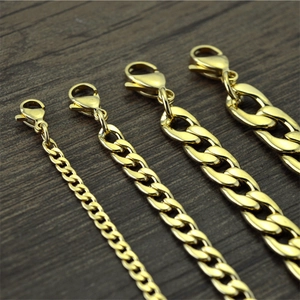 Golden stainless steel Cuban link chains in four sizes on a dark wooden background