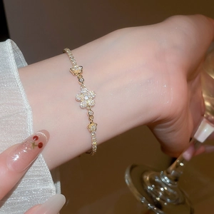 Detailed view of elegant gold flower bracelet with cubic zirconia on model's wrist