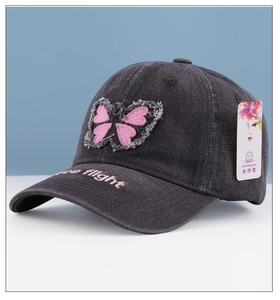 Close-up of pink butterfly patch and Free Flight embroidery on grey denim baseball cap