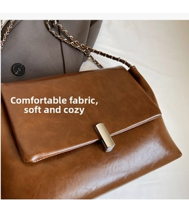 Close-up of brown vintage leather messenger bag with silver buckle and chain strap