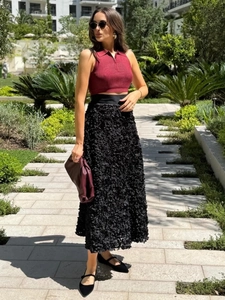 Detail of elegant black long skirt with 3D textured floral fabric and layered design