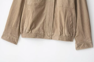 Detail of faux suede jacket featuring elastic hem and utility flap pocket in tan