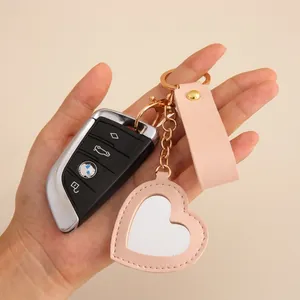 Close-up of heart-shaped pink PU leather keychain with gold metal ring and strap