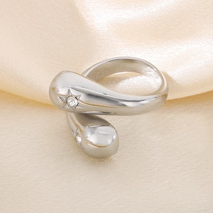 Close-up of silver teardrop ring with star engraving and small diamond on silk background