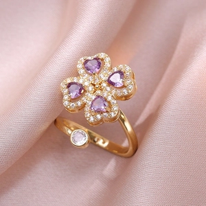 Golden clover ring featuring a purple heart-shaped stone on elegant pink silk fabric
