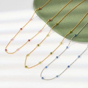 Detail of colorful beaded stainless steel necklaces with gold and silver chains on green fur