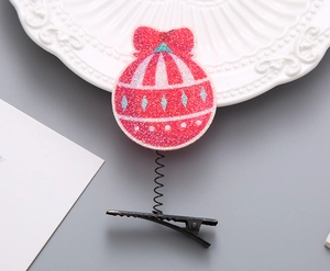 Detail eines glitzernden rosa Weihnachtskugel-Haarclips mit Feder und Metall-Entenschnabel-Clip
