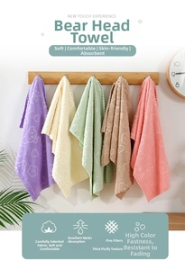 Detail of coral fleece towel set with embossed bear and flower patterns hanging on wooden rack