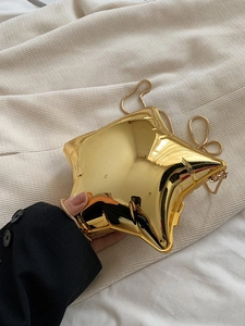 Detail view of a gold star-shaped evening bag with a metallic finish and a fine chain strap