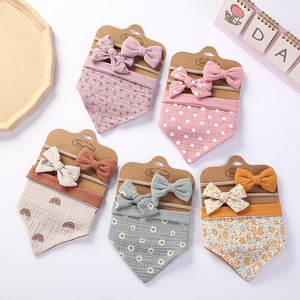 Flat lay of baby cotton bibs and matching floral headbands on a clean white background