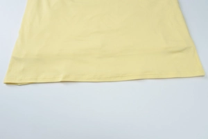 Detailed close-up showing the smooth fabric texture and hem stitching of the pale yellow dress
