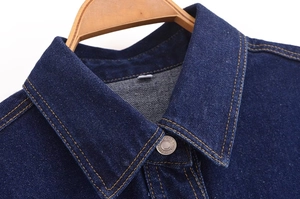 Detailansicht eines dunkelblauen Jeanshemdkragens mit Metallknopf und orangefarbenen Nähten