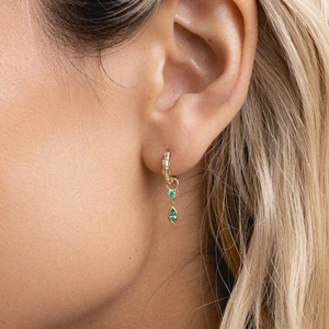 Detail view of gold huggie earring with green round and marquise-cut crystal charms