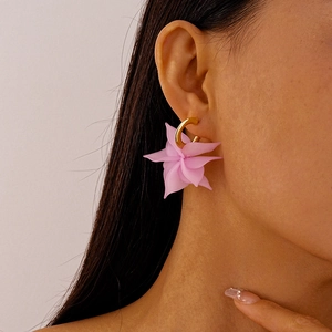 Detailed view of pink acrylic flower earrings with gold C-shaped metal hooks on a model
