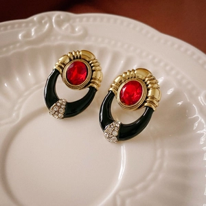 Vintage gold earrings with red oval faux gemstones and rhinestones on a relief plate