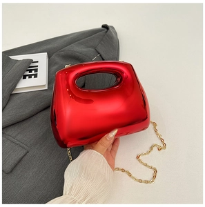 Detail of red acrylic crossbody bag with shiny finish and gold metal chain strap