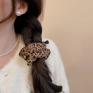 Close-up of fluffy leopard print fabric hair scrunchie worn on a braided hairstyle