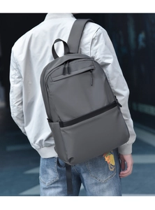 Rear view of a grey nylon laptop backpack with leather details on an urban model
