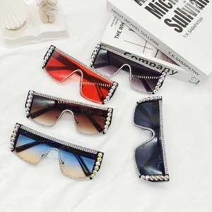 Lunettes de soleil oversize avec strass colorés présentées sur un tissu blanc
