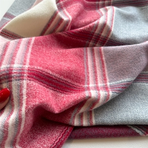 Close-up of red and grey plaid cashmere-like scarf showing soft wool texture and fringe
