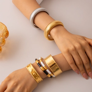 Stylish gold and silver stainless steel snake chain bracelets on woman's crossed wrists