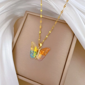 Detail of a gold-plated butterfly pendant featuring colorful resin wings and pavé crystals