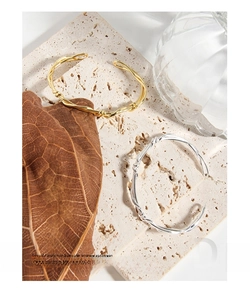 Detailed view of woven vine twisted open bangles in gold and silver finish