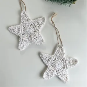 Close-up of white knitted Christmas star ornaments with gold glitter and hemp ropes