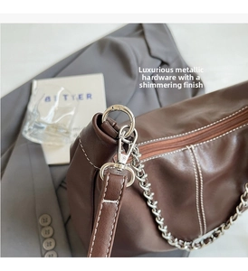 Detail of premium brown leather bag showing white contrast stitching and silver chain strap