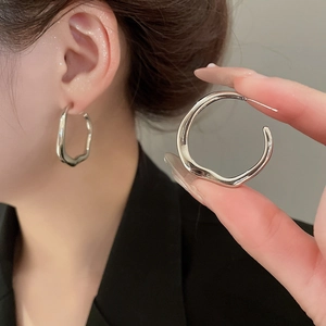 Detail view of silver irregular wavy hoop earrings with polished metallic finish