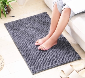 Close-up of soft dark grey chenille bathroom mat texture on light wood flooring