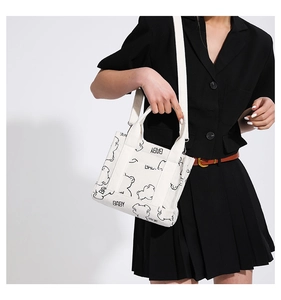 White corduroy crossbody bag with cute bear print shown on a model in a black suit