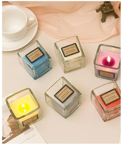 Flat lay of colorful square glass scented candles with glowing wicks and decor