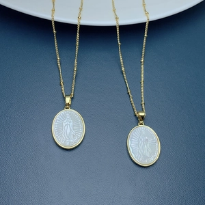Detailed view of oval white mother of pearl Virgin Mary pendant on gold satellite chain